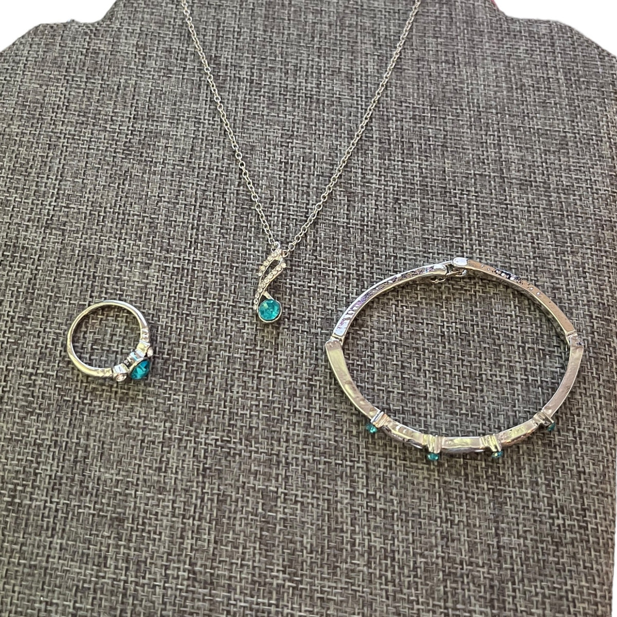 Set of silver jewelry with turquoise stones on a textured gray surface