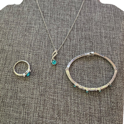 Set of silver jewelry with turquoise stones on a textured gray surface
