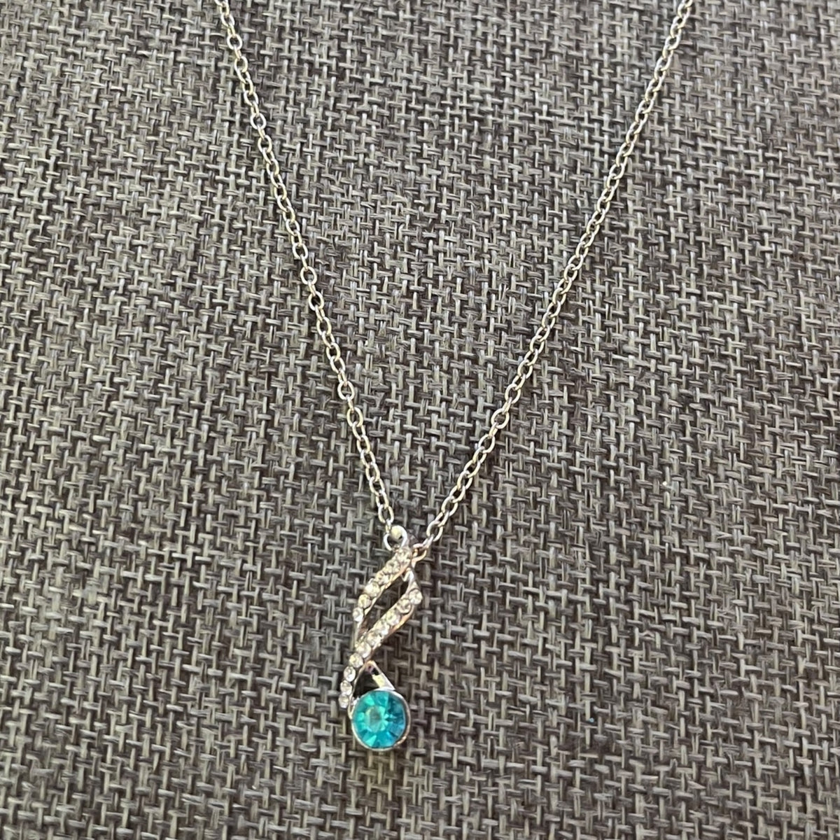 Necklace with a blue gemstone pendant on a textured gray background