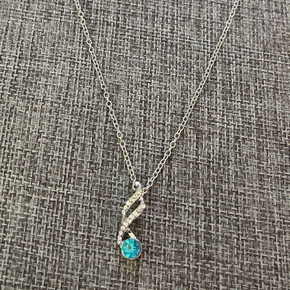 Necklace with a blue gemstone pendant on a textured gray background
