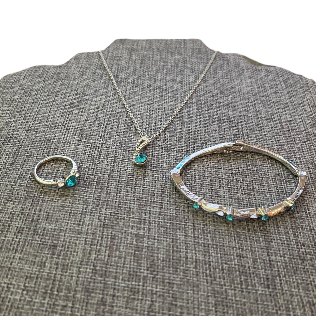 Silver jewelry set with ring, bracelet, and necklace on a textured gray surface