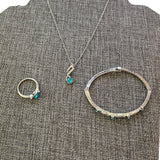 Set of silver jewelry with blue stones on a textured gray surface