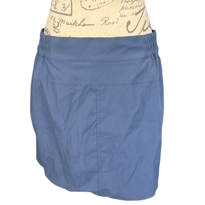 Blue skort worn over a patterned garment on a white background