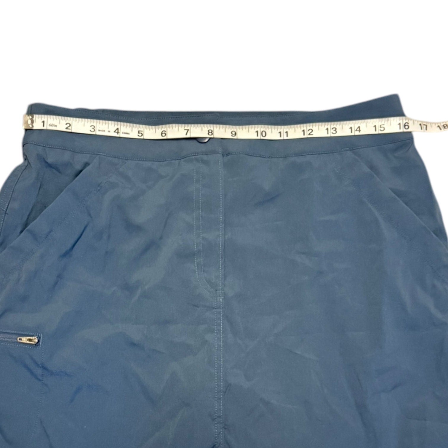 Blue skorts with a measuring tape draped over them on a white background
