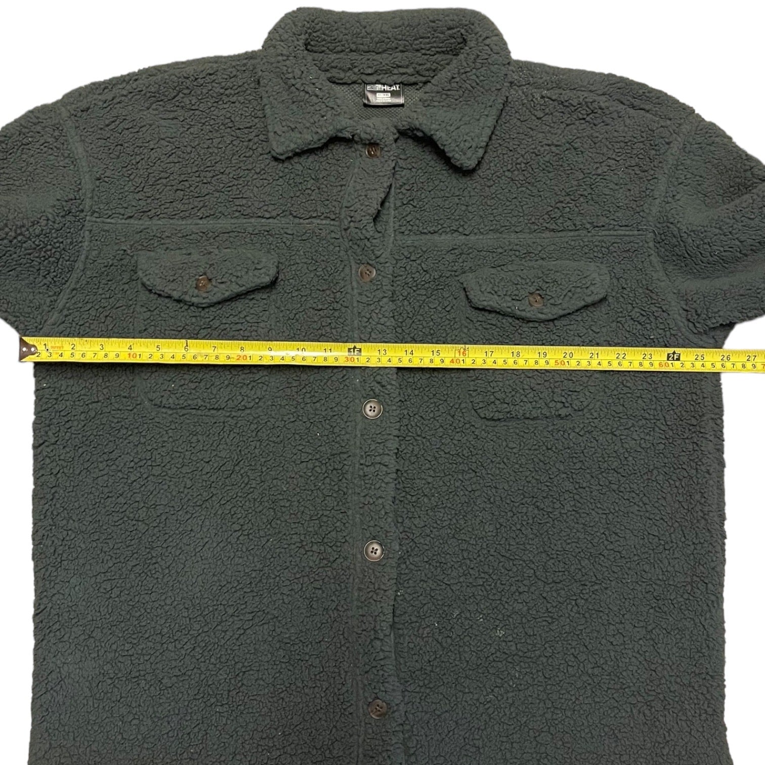 Gray fleece shirt with a measuring tape across it on a white background