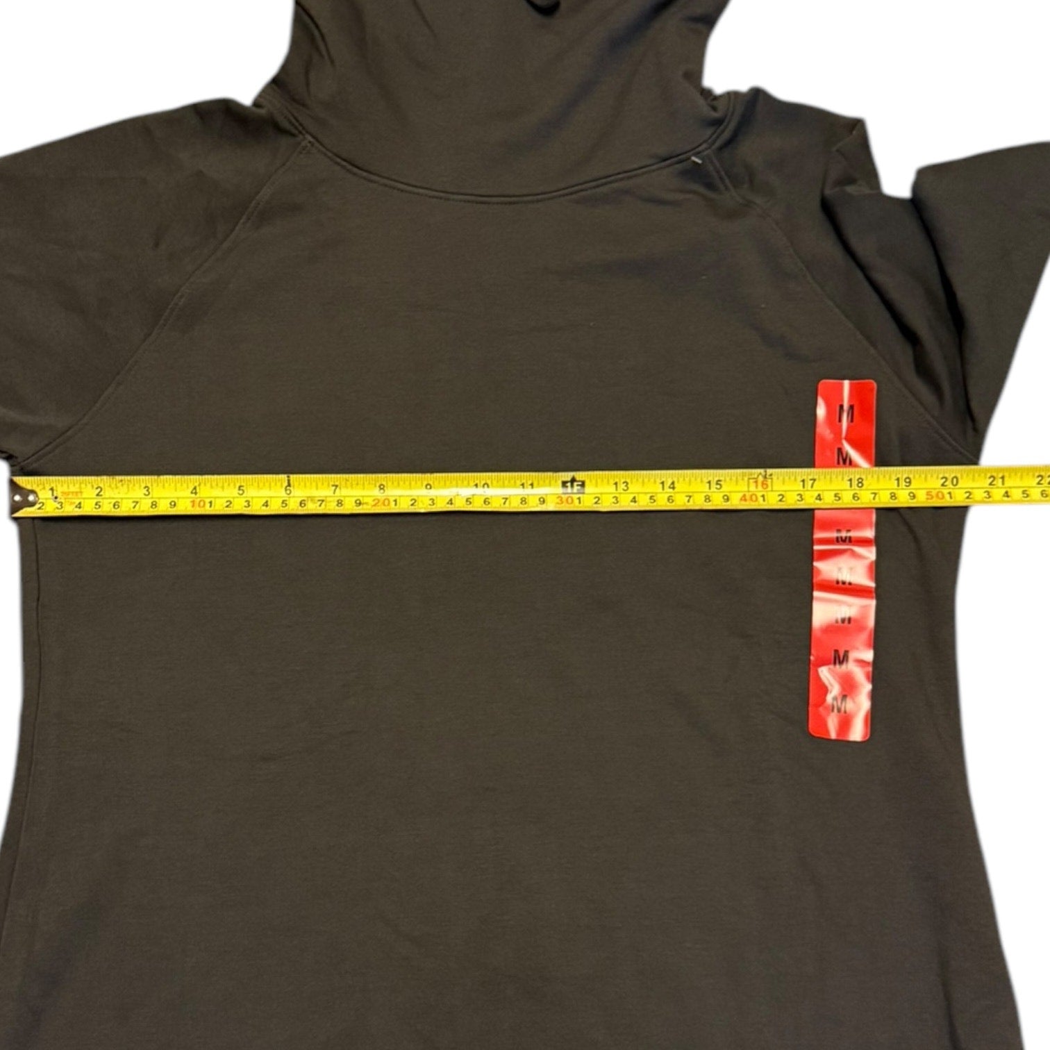 Green pullover with a measuring tape and size tag on a white background