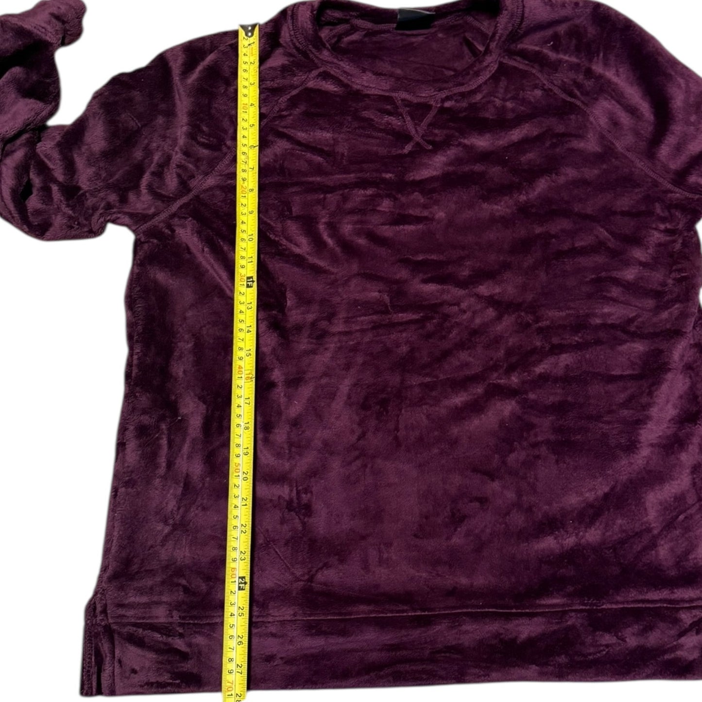 A purple long-sleeve velour shirt shown flat on a white background with a yellow measuring tape vertically aligned to indicate its size.
