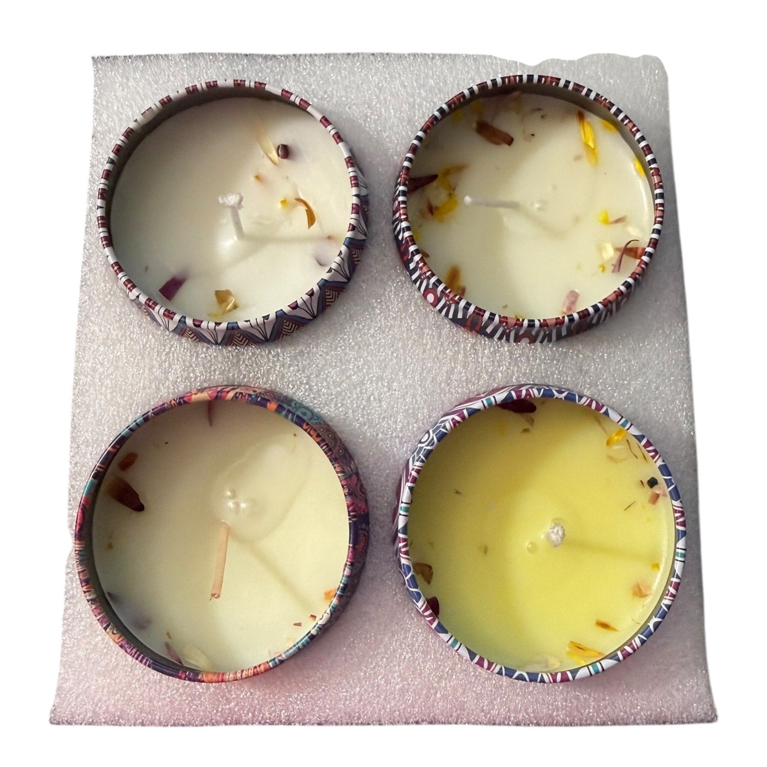 Four small candles in decorative holders on a textured surface