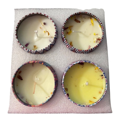 Four small candles in decorative holders on a textured surface
