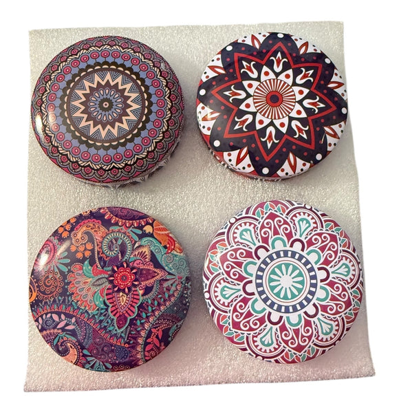 Four colorful mandala candle containers on a light foam background