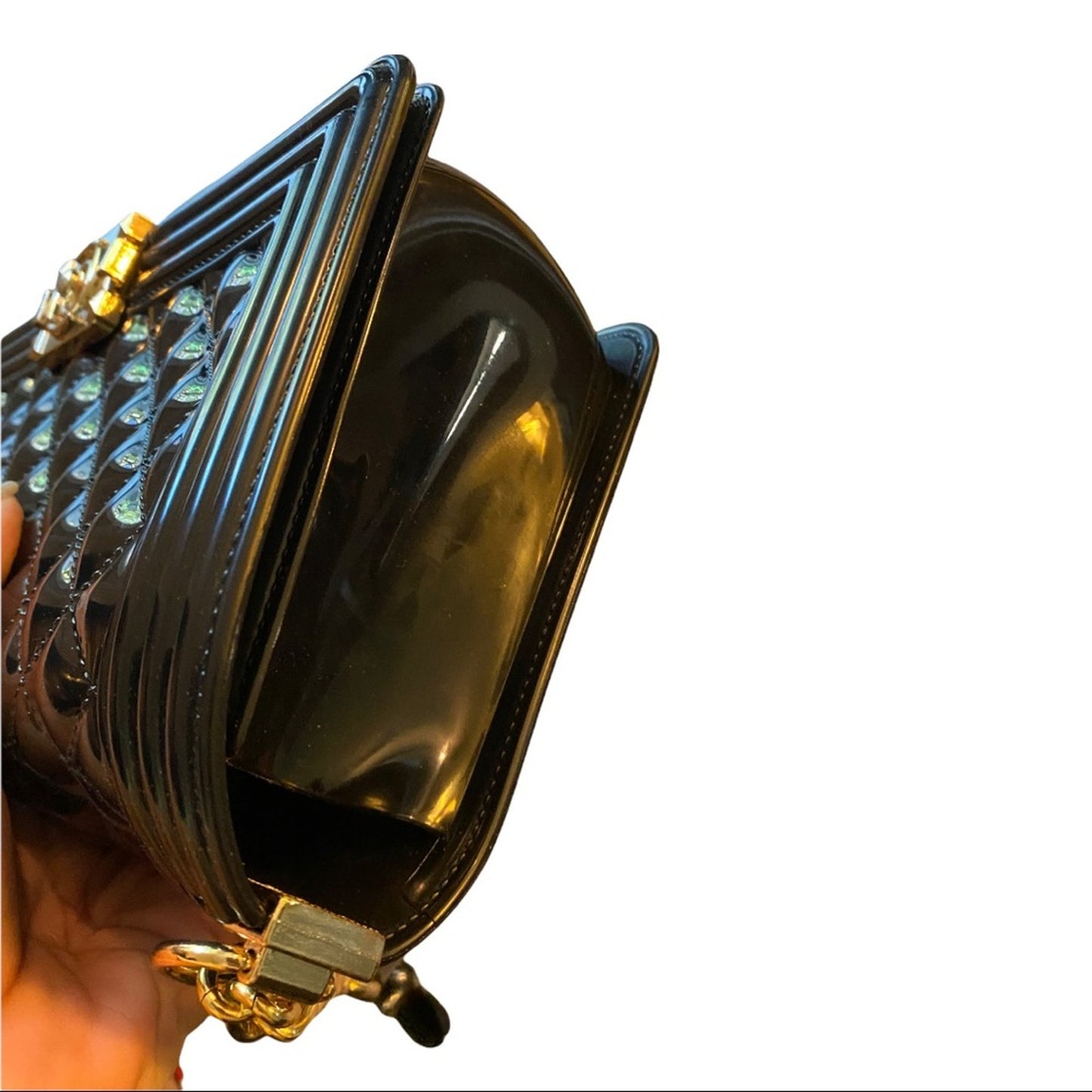 Side of black quilted bag held by a hand on a white background