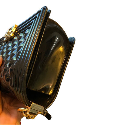 Side of black quilted bag held by a hand on a white background