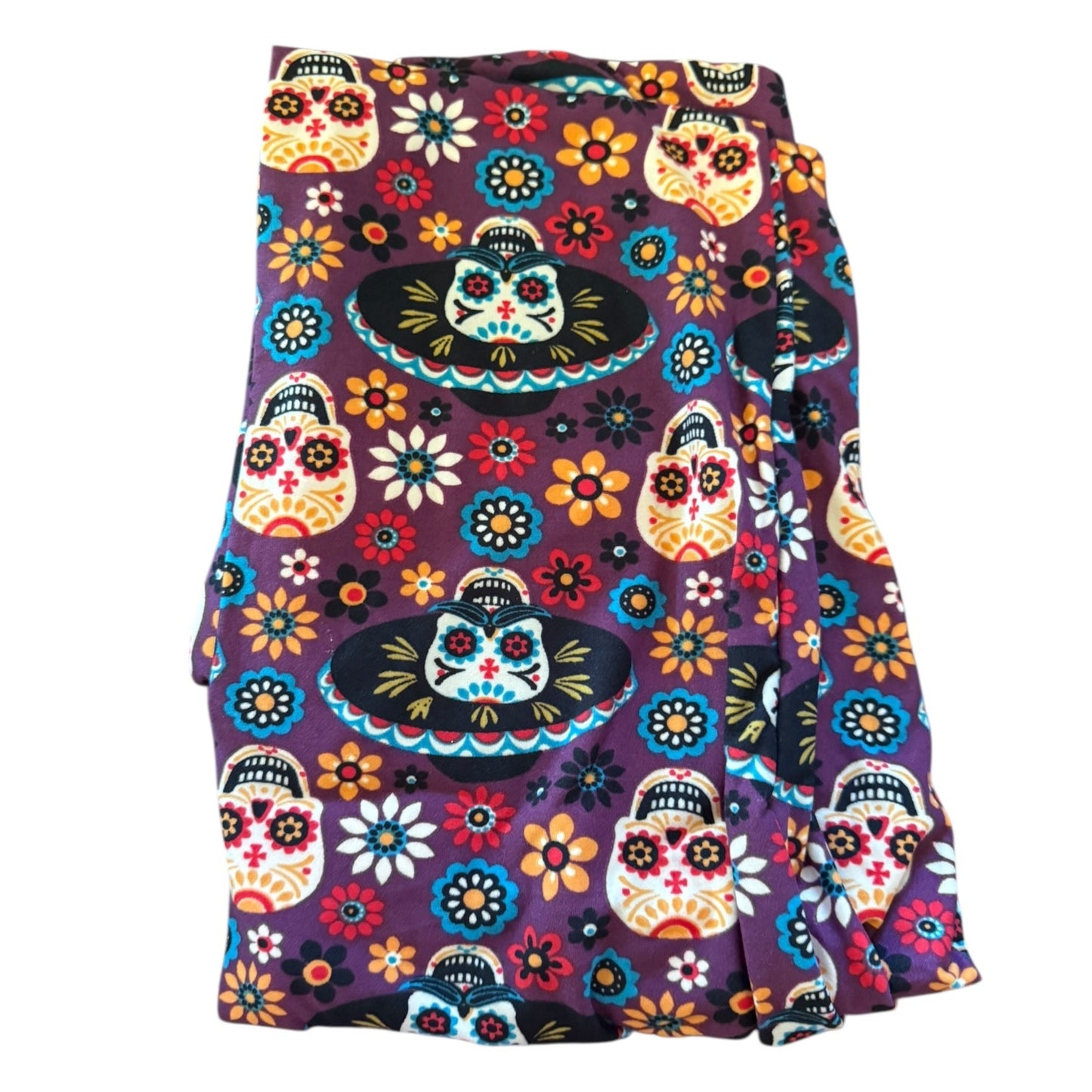Colorful sugar skull pattern leggings on a purple fabric background