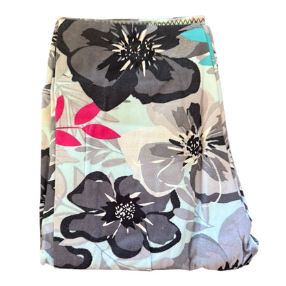 A folded leggings with floral print with dark gray, black, and light gray flowers, pink leaves, and a light blue background.