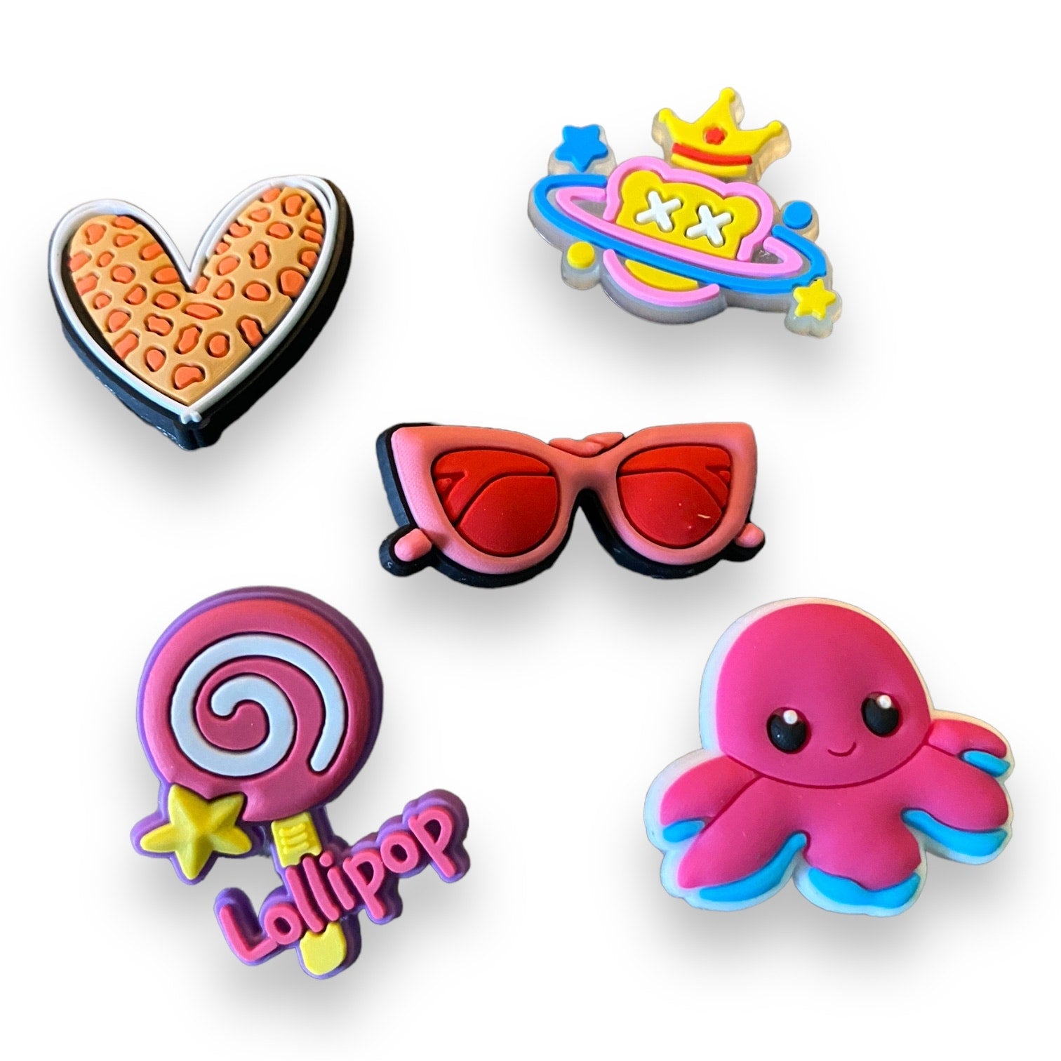 Set of colorful shoe charms including a heart, sunglasses, lollipop, and octopus on a white background.
