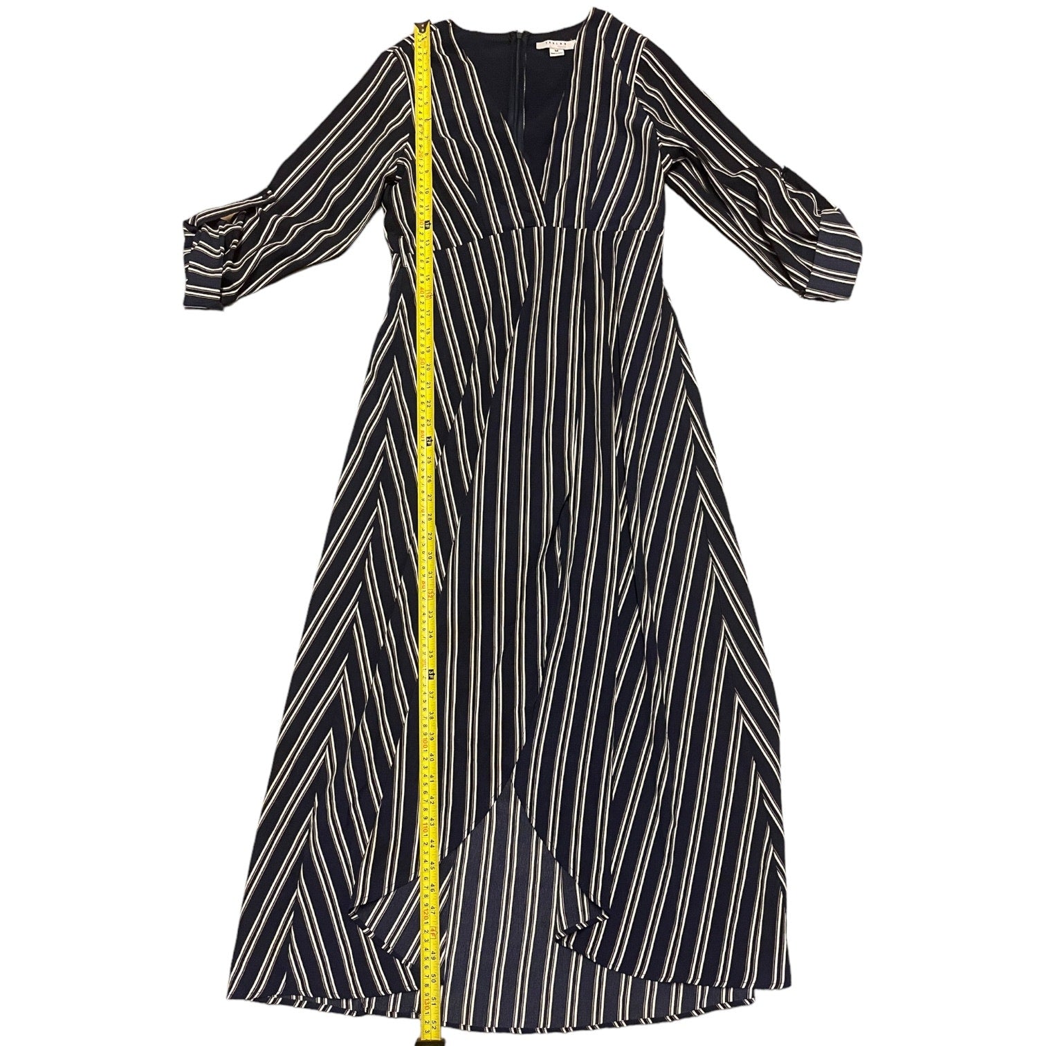 A blue midi dress with vertical white stripes and a yellow measuring tape draped down the front, shown against a plain white background.