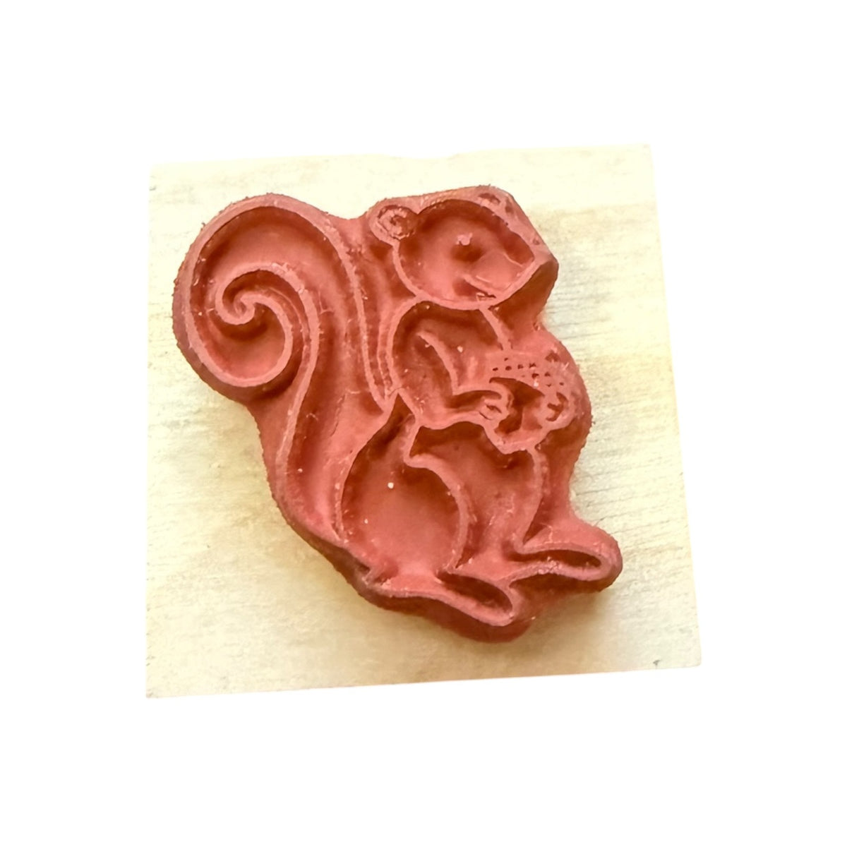 Red squirrel-shaped stamp on a beige background