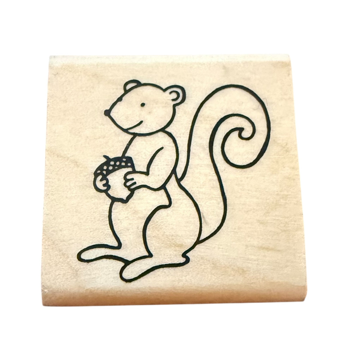 Wooden stamp with a cartoon squirrel holding an acorn on a beige background