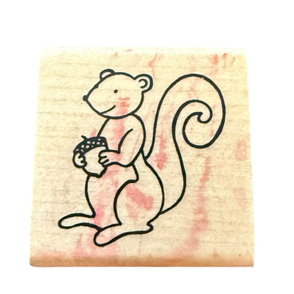 Rubber stamp with a cartoon squirrel holding an acorn on a pink and beige background