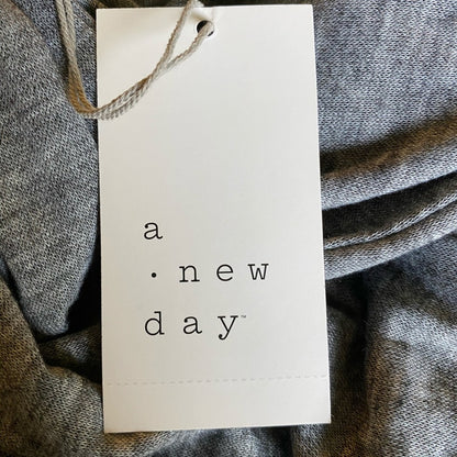 White tag with 'a new day' text on a textured gray fabric background
