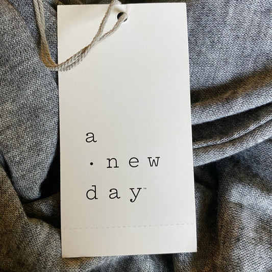 White tag with 'a new day' text on a textured gray fabric background