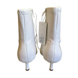 Back of a Pair of white ankle boots with a tag on a white background