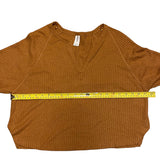 Brown textured shirt with a measuring tape laid across it on a white background