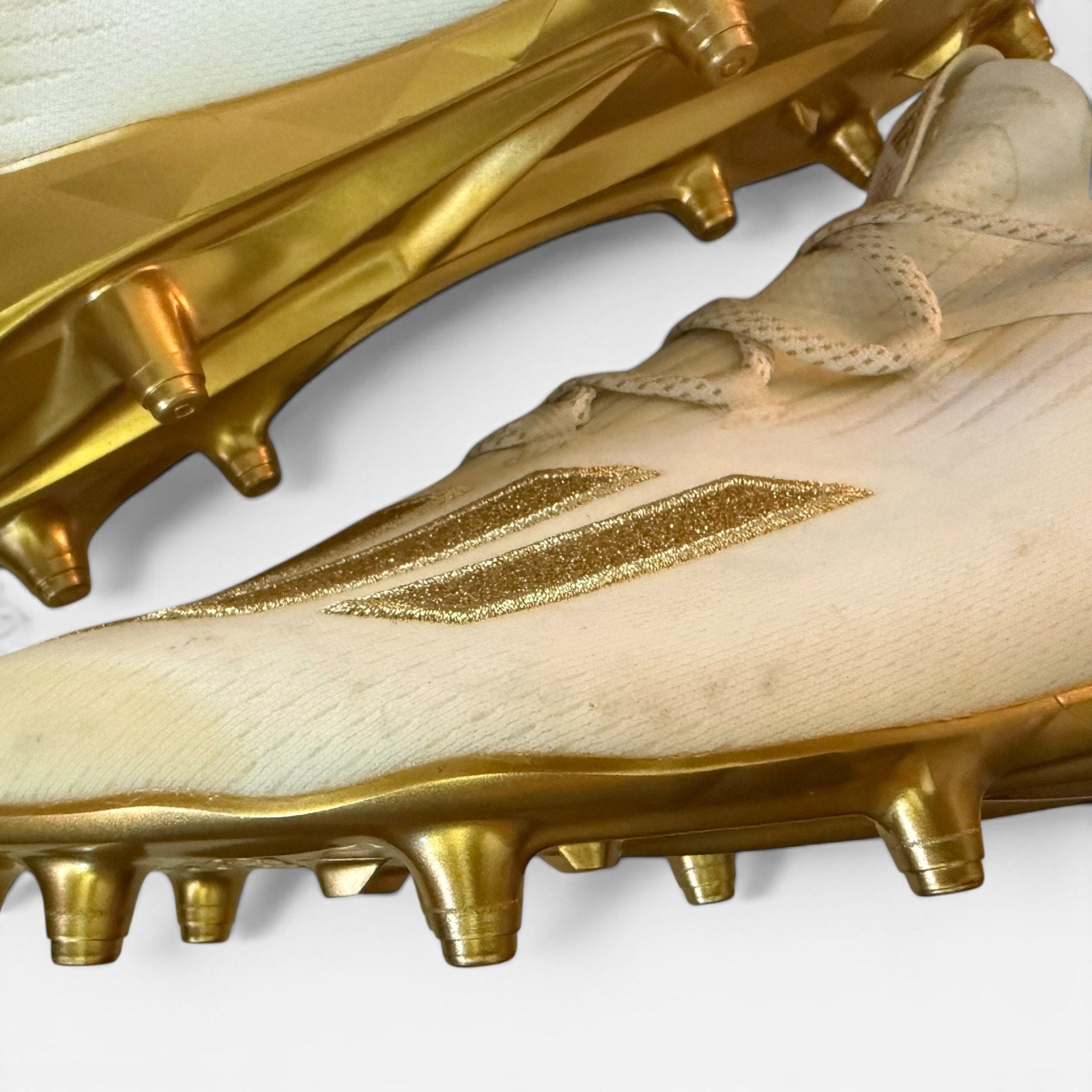 Gold soccer cleats showing issues with a brand logo on a white background
