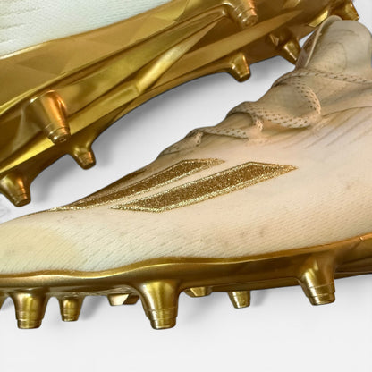 Gold soccer cleats showing issues with a brand logo on a white background