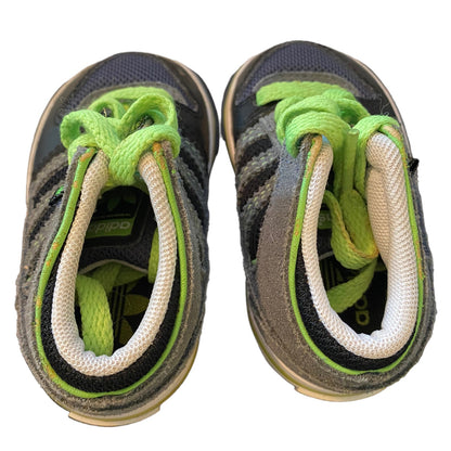 Pair of children's shoes with green and white laces on a white background