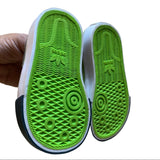 Green sole of a shoe with Adidas logo held by a hand on a white background