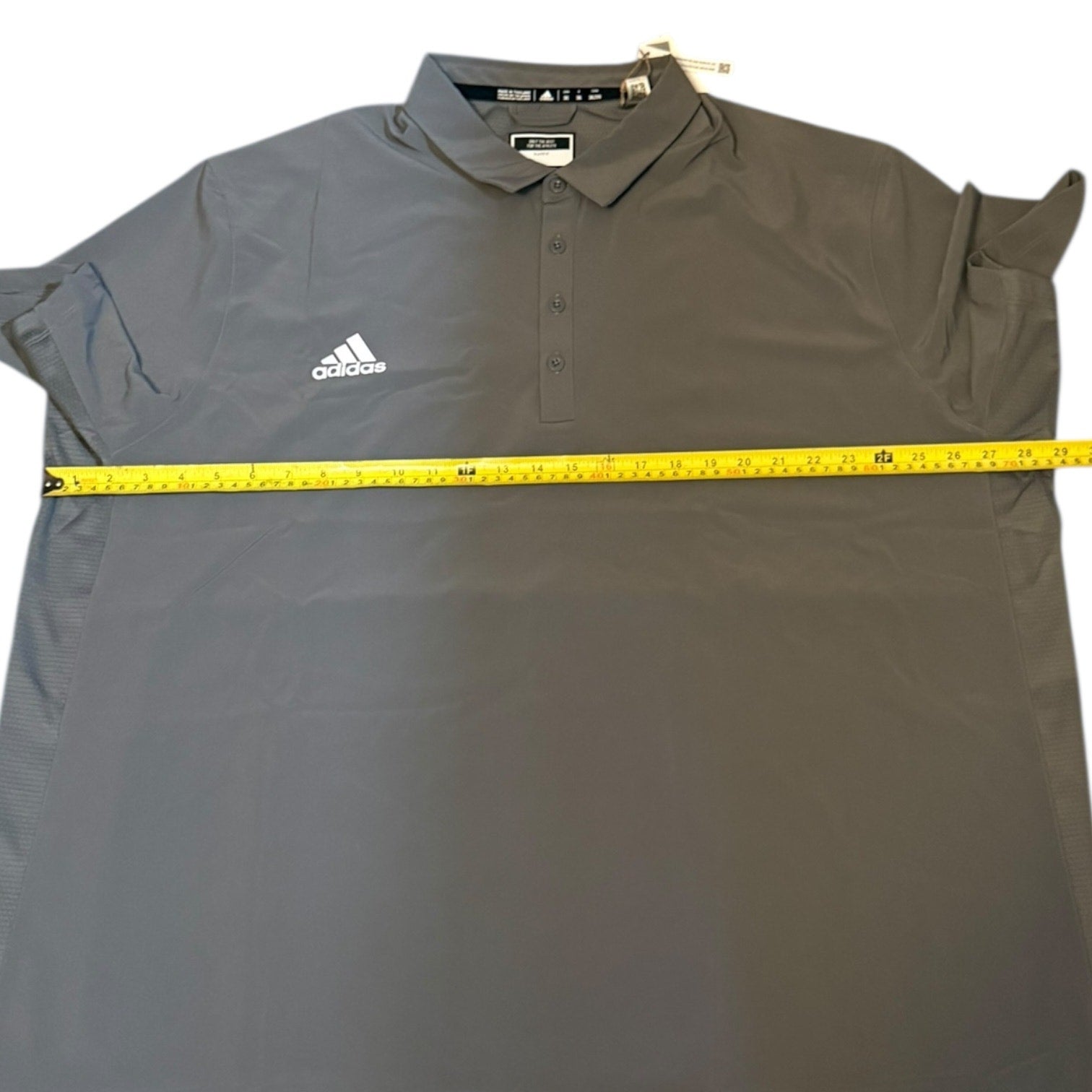 Gray Adidas polo shirt with a measuring tape on a white background