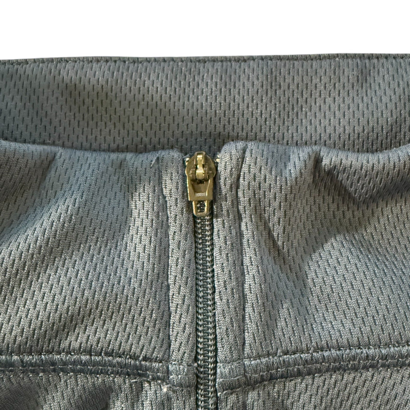 Close-up of a gray jacket with a gold zipper on a white background