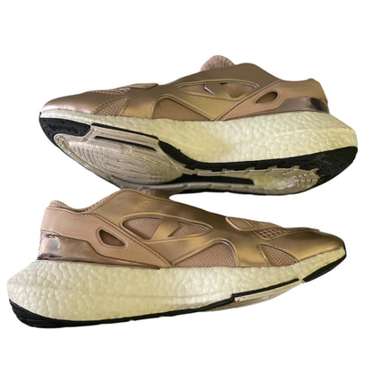Side view of rose gold running shoes with white soles on a white background