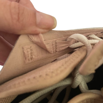 Issue on shoe with a brand label, held by a hand against a white background.