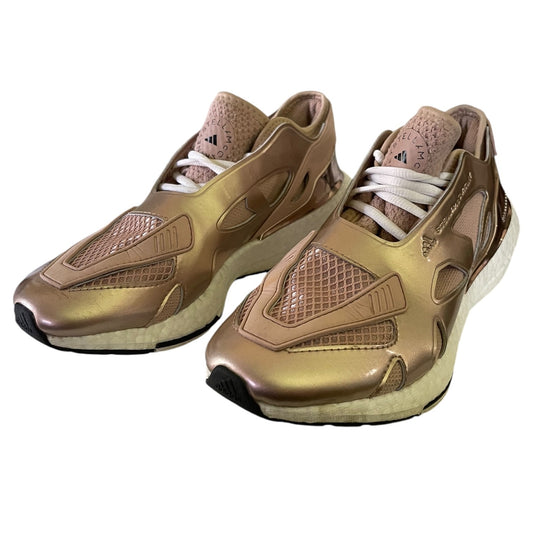 Pair of rose gold Adidas sneakers on a white background