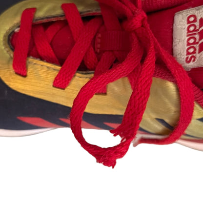Close-up of a sneaker with red laces and damage to lace and a visible Adidas logo.