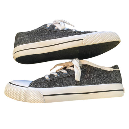 A pair of low-top canvas sneakers with a dark gray  upper, white laces, and off-white rubber soles, shown against a plain white background.