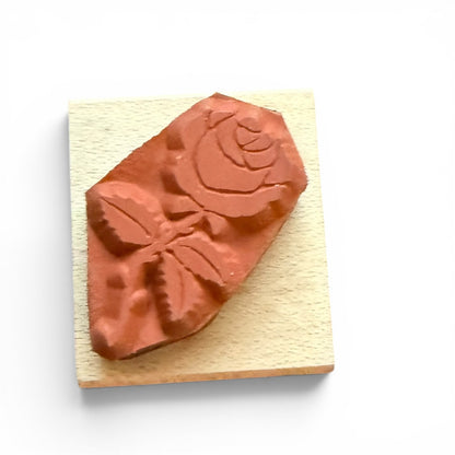 Rose-shaped stamp on a wooden block with a white background