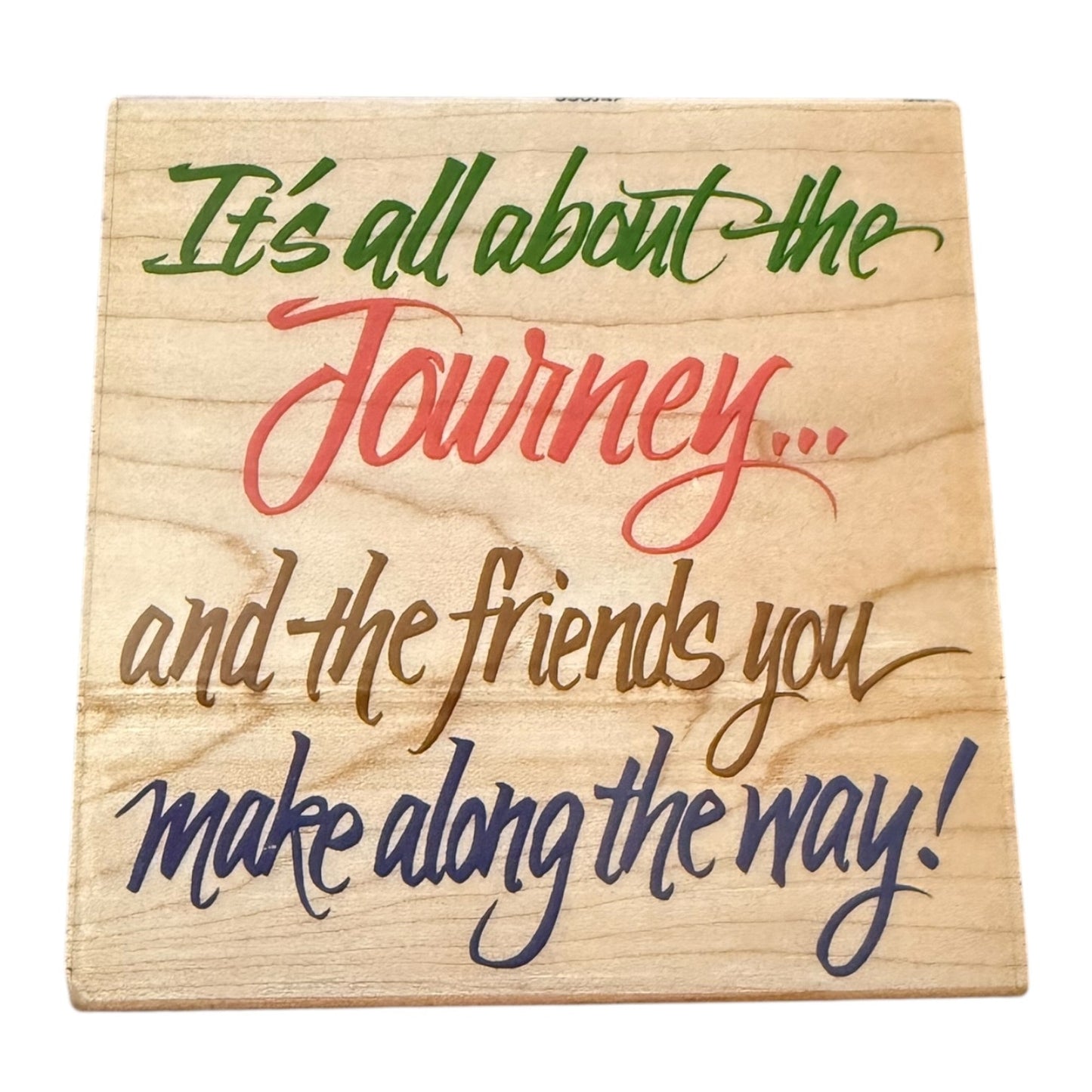 Wooden stamp with motivational quote in colorful text on a white background