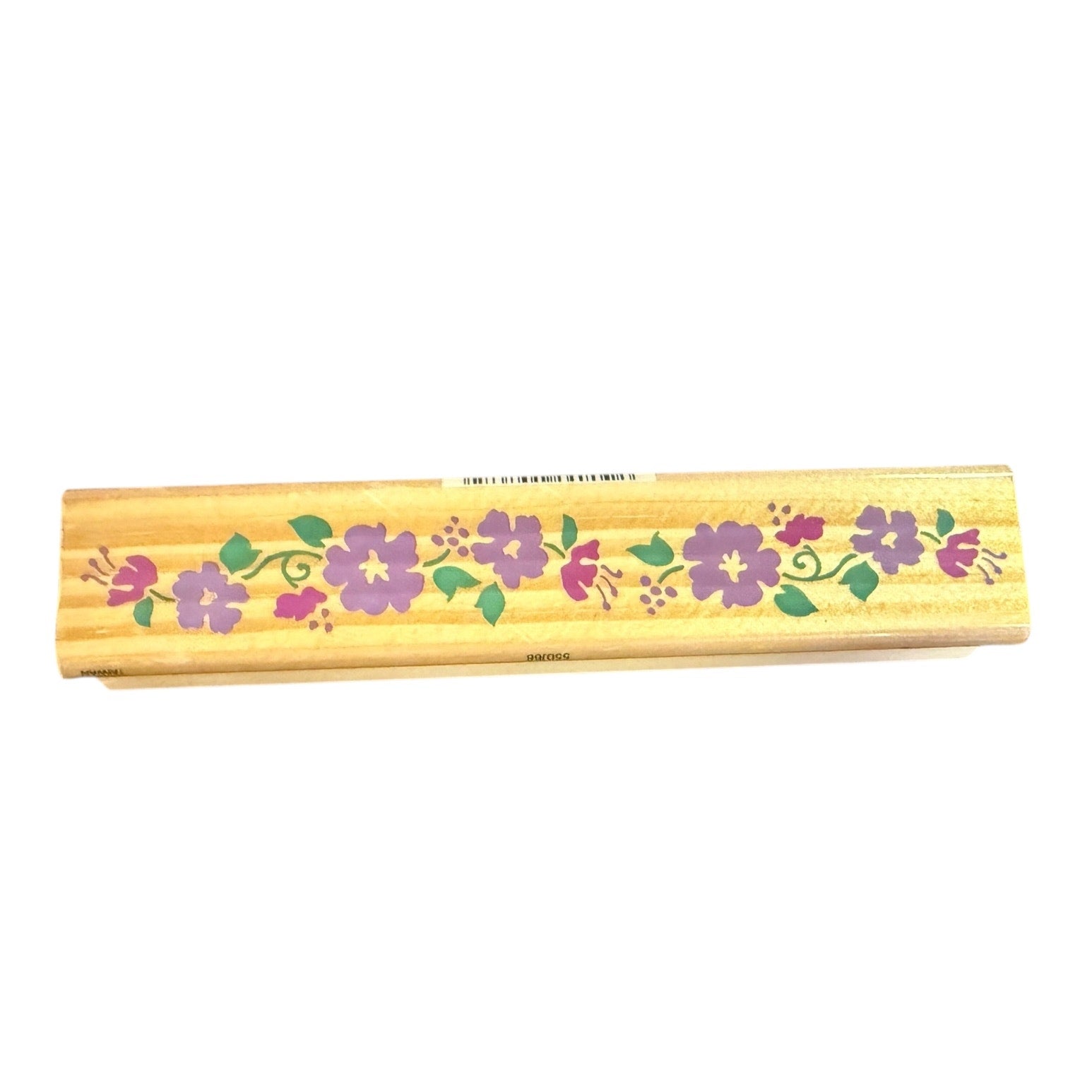 A rectangular wooden stamp with a light natural wood finish, decorated with a horizontal floral pattern of purple hibiscus flowers and green leaves, shown against a plain white background.