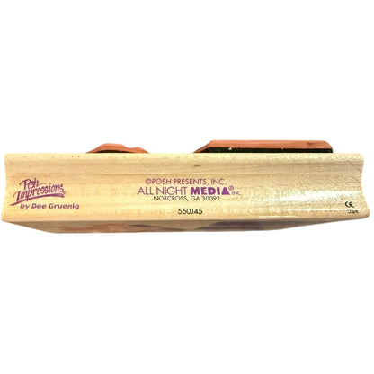 A close-up side view of a wooden stamp with printed branding and text, including 'Posh Impressions by Dee Gruenig' and 'All Night Media'.