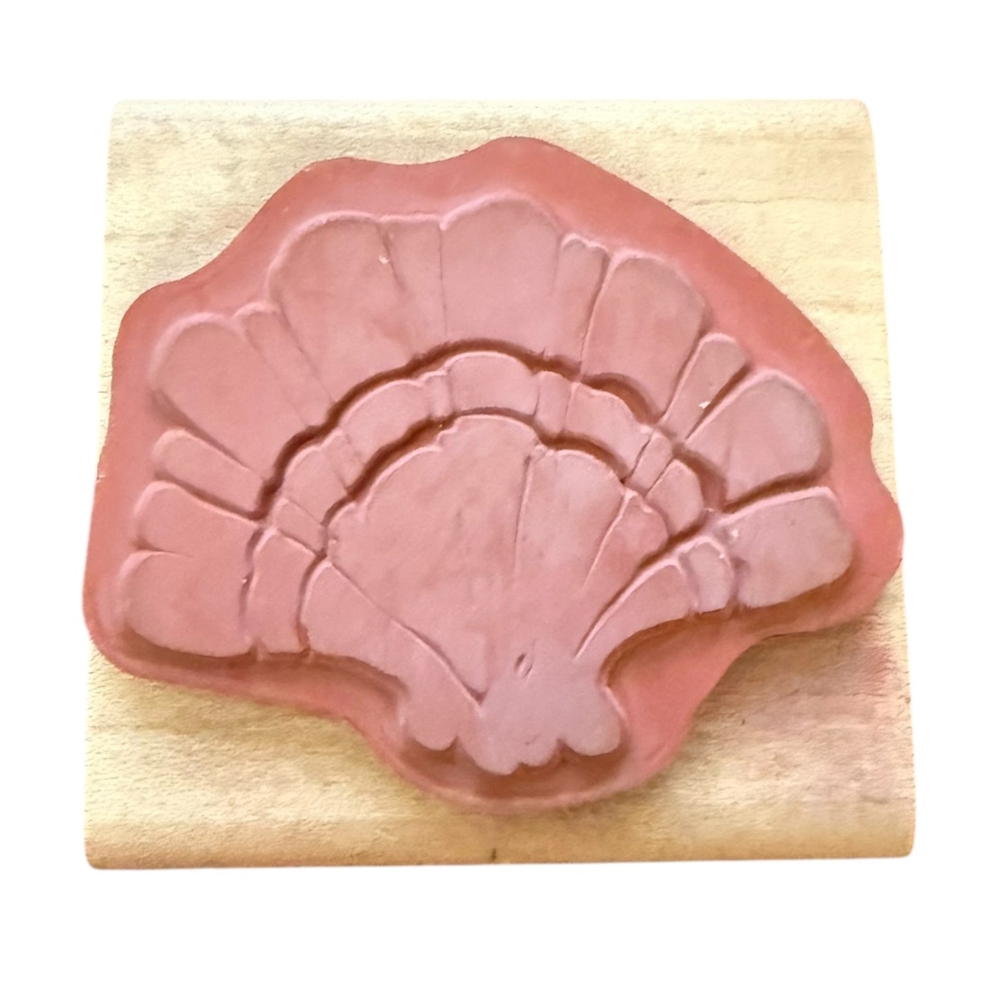 Pink shell-shaped rubber stamp on a wooden block