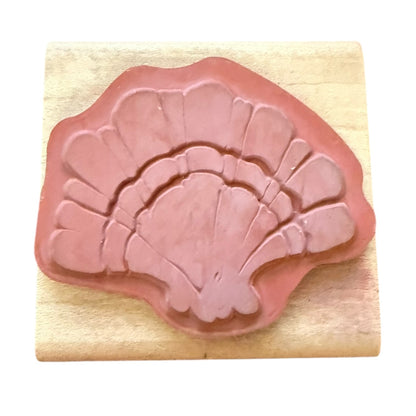 Pink shell-shaped rubber stamp on a wooden block