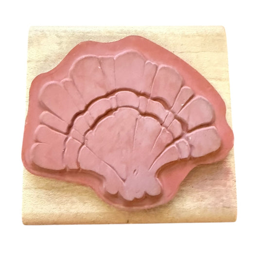 Pink shell-shaped rubber stamp on a wooden block