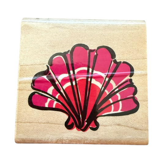 Wooden stamp block with a pink shell design on a white background