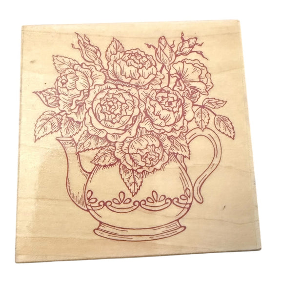 Wooden stamp with floral design of a teapot and flowers on a white background