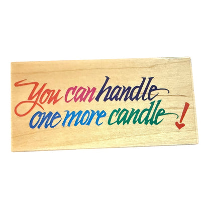 A rectangular wooden block with the phrase 'You can handle one more candle!' written in colorful script. 