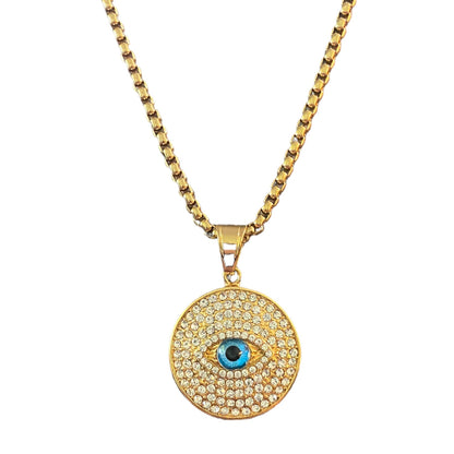 A gold-toned chain necklace with a round evil eye pendant paved with small clear stones, featuring a blue and black eye center.
