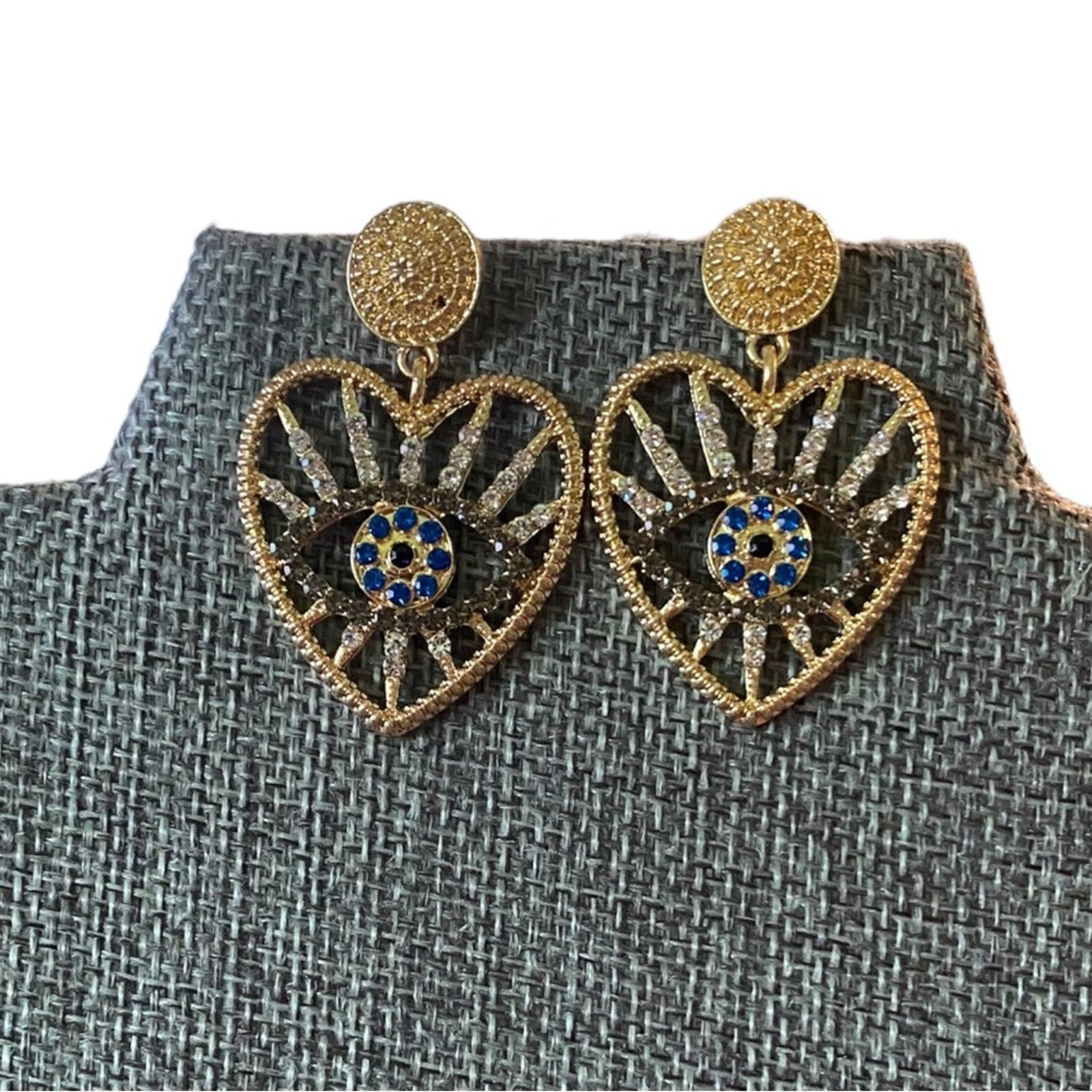 Heart-shaped earrings with gold and blue design on a textured gray background